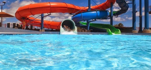waterpark with aqua blue glistening water and a long blue and red slide